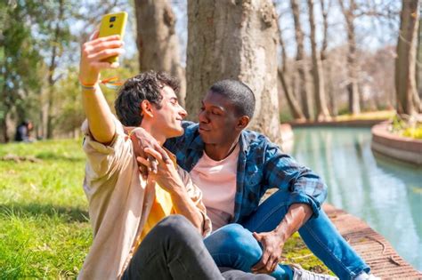 Selfie de um casal gay multiétnico conversando no parque por um conceito de rio lgbt Foto Premium