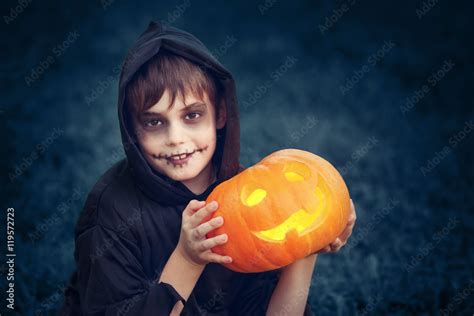 Child in scary costume holding pumpkin ln. Child in halloween outfit at ...