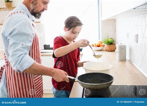 Mature Father With Small Son Indoors In Kitchen Making Pancakes Stock