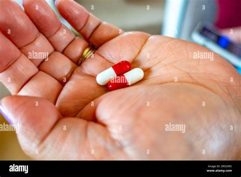 A Female Hand Holding Red And White Paracetamol Capsules An Off The