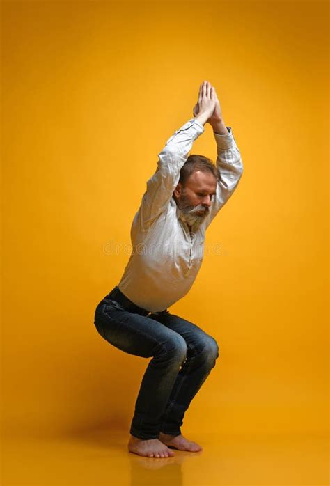 Old Man Practicing Yoga Doing Stretching Exercises Against Yellow