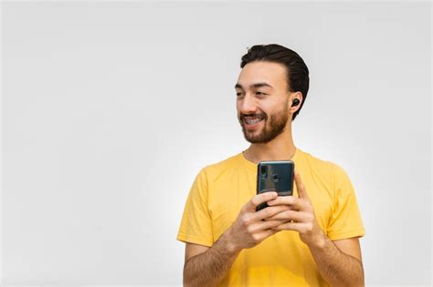 Gay queer joven latino con auriculares inalámbricos mirando hacia otro lado mientras sonríe