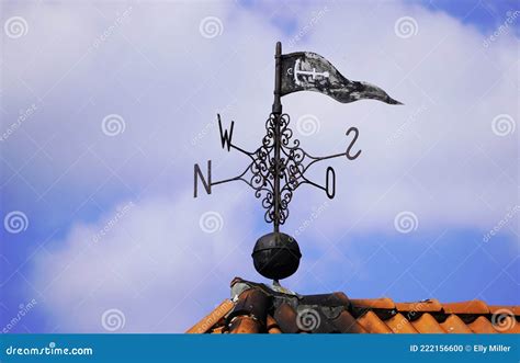 Old Metal Weather Vane On The Roof Of A Building With The Four Cardinal