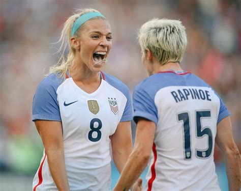 Two Female Soccer Players Standing Next To Each Other With Their Mouths