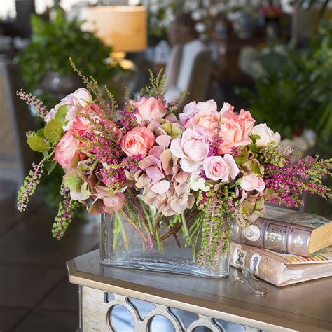 A Vase Filled With Pink Flowers Sitting On Top Of A Table Next To A Book