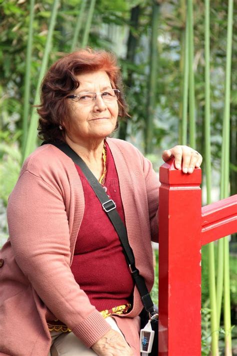 80 Year Old Latina Woman Sitting In The Garden With A Smile In Solitude Spending Her Retirement