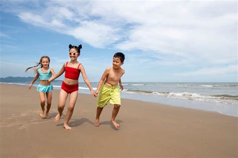 Ni Os De Tiro Completo Corriendo En La Playa Foto Gratis