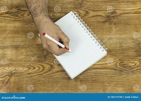 Escritura De La Mano En El Cuaderno En El Fondo De Madera De La Textura