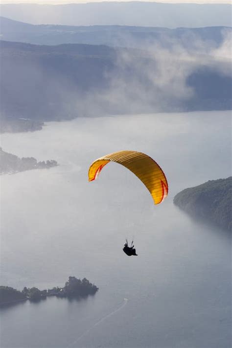 Faceless person flying paraglider over green countryside · Free Stock Photo