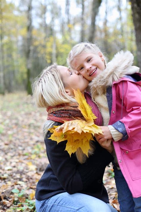Happy Blonde Mother Kisses Her Daughter With Maple Leaflets Stock Image