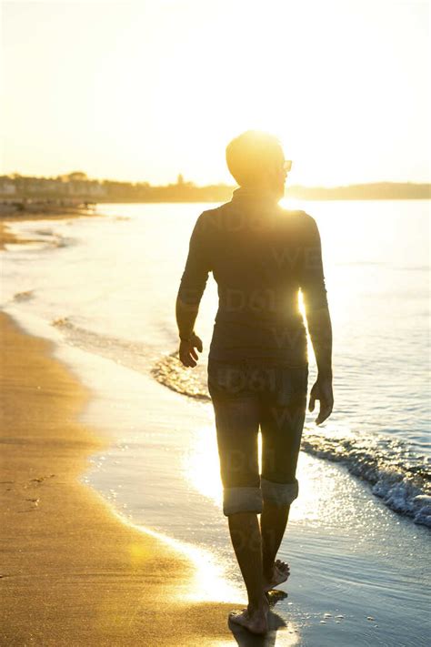 Silhouette Von Mann Zu Fu Am Strand Bei Sonnenuntergang Lizenzfreies