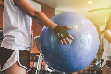 Premium Photo Midsection Of Woman Lifting Fitness Ball In Gym