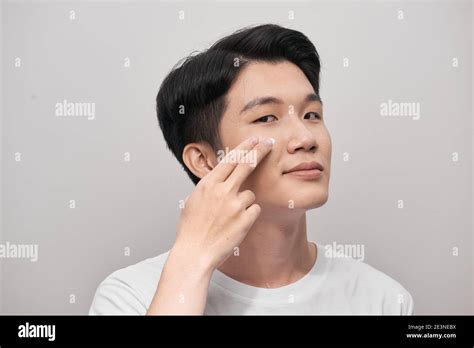 Skin Care Portrait Of Handsome Young Man Applying Cream To His Face