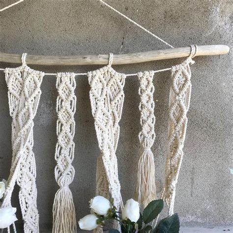 A Macrame Hanging From A Wall Next To Flowers