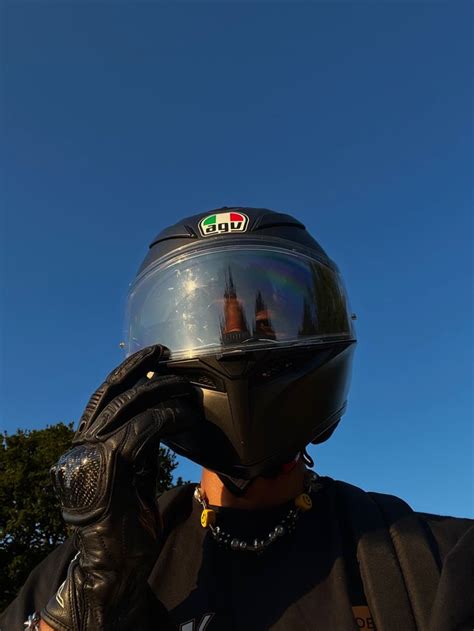 A Man Wearing A Motorcycle Helmet And Holding His Hand Up To His Face