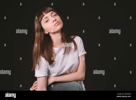 Portrait studio d une jolie femme brunette dans un t shirt blanc debout derrière la chaise qui