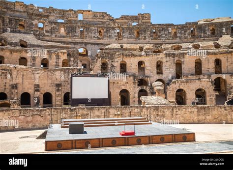 A Stage And Large Screen Set Up In The Arena Within The Towering Ruins