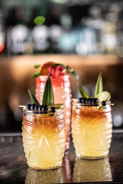 Cócteles mai tai en vasos hawaianos adornados con piña arándanos y