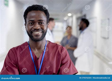 Unaltered Portrait Of Happy African American Male Doctor In Corridor