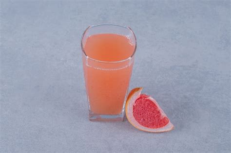 Suco De Toranja Fresco E Uma Fatia De Fruta Na Superf Cie Cinza Foto