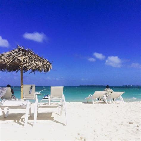 Two Lawn Chairs And An Umbrella On The Beach