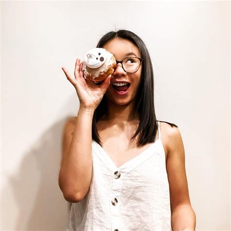 A Woman Holding A Doughnut Up To Her Face And Making A Funny Face With It