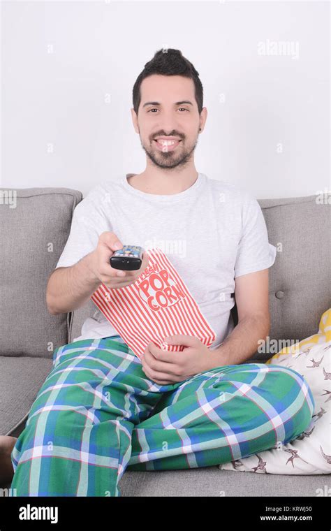 Young Man Eating Popcorn And Watching Movies Relaxed On Couch Indoors