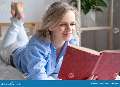 Blonde Woman Holding Open Book And Reading Lying On Bed Leisure Stay Home And Quarantine Stock