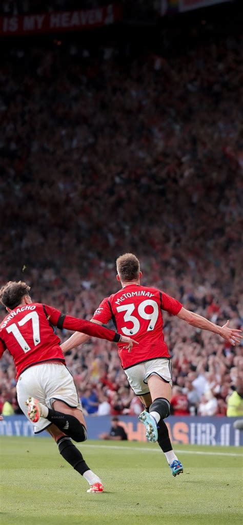 Two Men Playing Soccer On A Field With Fans In The Bleachers Behind Them