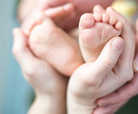 Os Pés Do Bebê Recém nascido Nas Mãos Da Mãe Forma Da Lareira Imagem