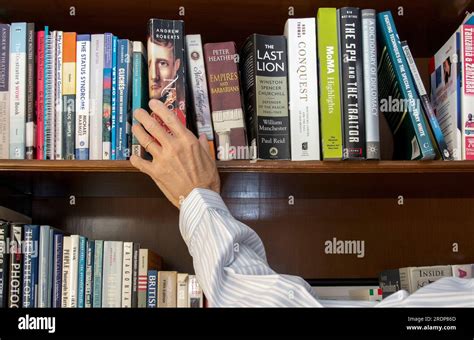 Hand reaching up for a book on library shelf Stock Photo - Alamy