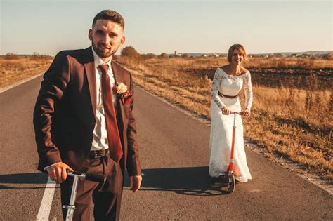 Pareja De Novios Sonriente Montando En Scooters A Lo Largo De La