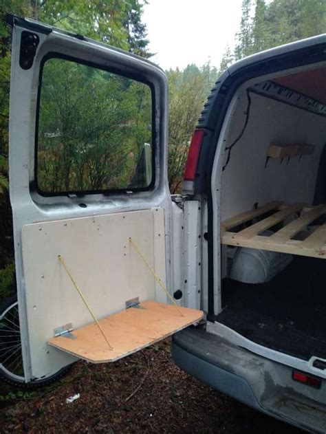 The Back End Of A White Van With Its Doors Open And Wood Flooring In Place