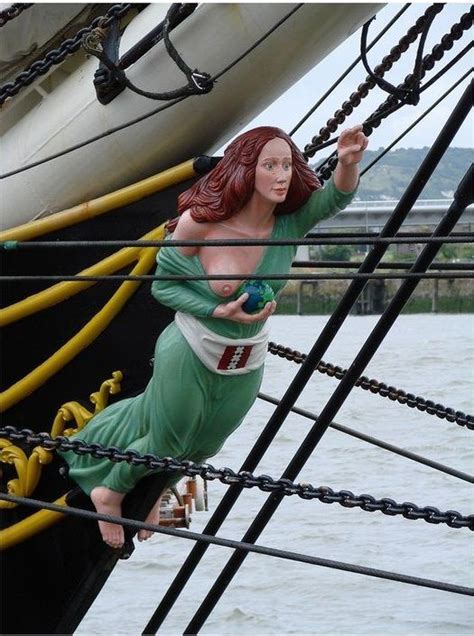 A Statue Of A Woman Hanging From The Side Of A Boat In The Water