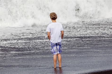 El Muchacho Se Divierte En La Espuma En La Playa Volcánica Negra Imagen