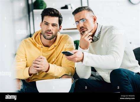 Pensive Son And Mature Father Watching Tv Together On Weekend At Home Stock Photo Alamy