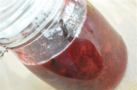 A Jar Filled With Red Liquid Sitting On Top Of A Wooden Table