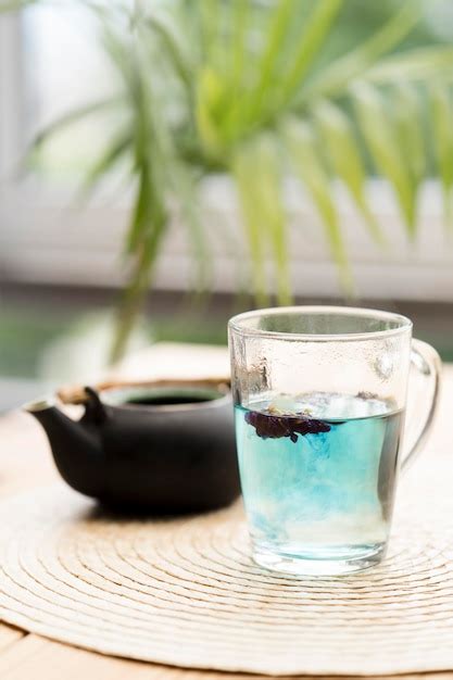 Té azul en vaso cerca de tetera Foto Gratis