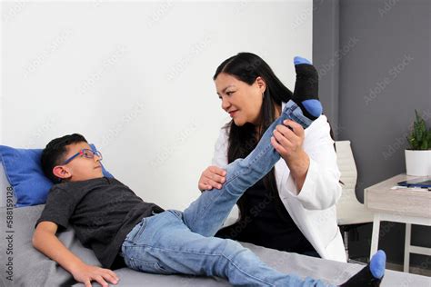Latina Pediatrician Woman Doctor Attends A Year Old Boy In Her Office Checks His Leg Knee And