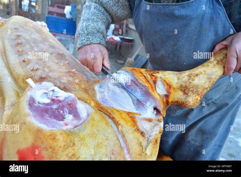 La Mitad Del Torso Masculino De Carnicero Cortando La Pierna De Cerdo