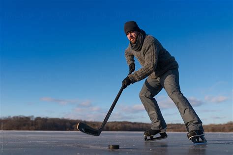 Man Skating With Puck Outdoors Playing Ice Hockey On Frozen Pond In