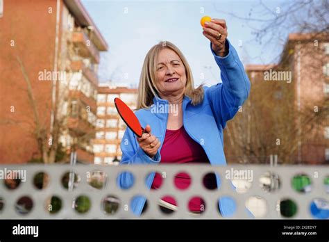 Mature Woman Holding Table Tennis Ball And Rackets In The Garden