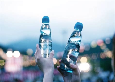 Two People Holding Up Water Bottles In The Air