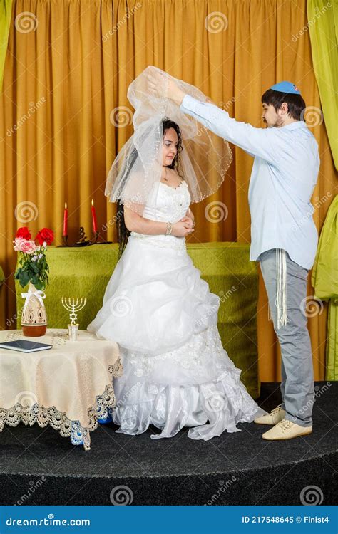 During The Chuppah Ceremony At A Synagogue Wedding The Groom Lifts The