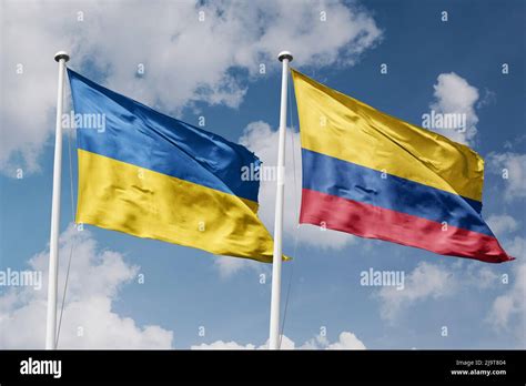 Ukraine And Colombia Two Flags On Flagpoles And Blue Cloudy Sky