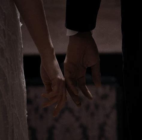 The Bride And Groom Hold Hands As They Stand Close Together