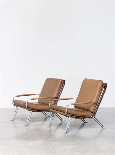 Two Brown Leather Chairs Sitting Next To Each Other On Top Of A Cement