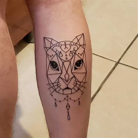 A Person With A Tattoo On Their Leg That Has A Cat S Face In The Middle