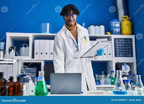 African American Man Scientist Using Laptop Holding Clipboard At