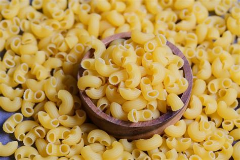 Macarrones crudos sobre pasta de tazón de madera sin cocer sobre fondo